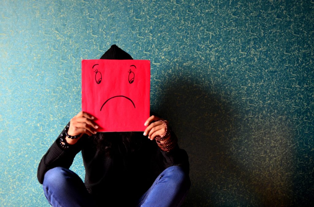 person holding up sad face sign