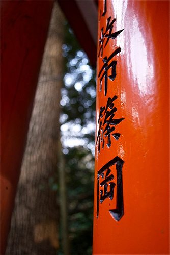 Chinese characters engraved on a red painted wooden pole.