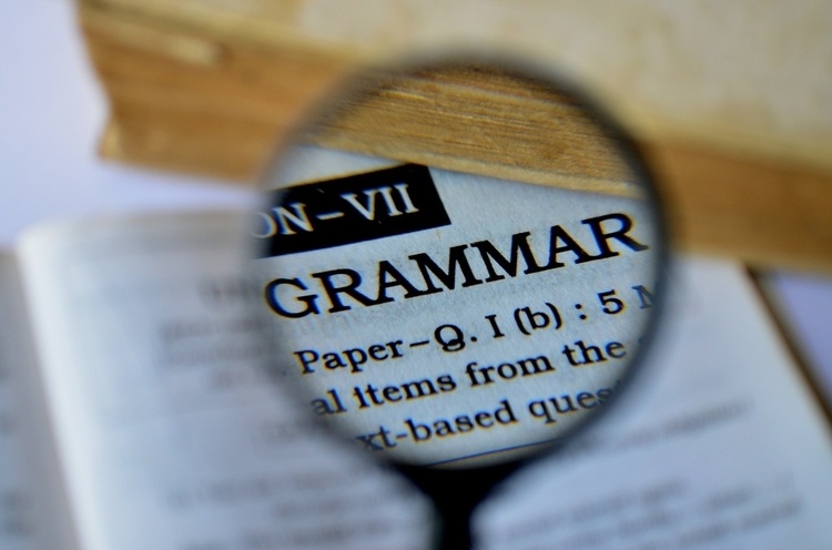 magnifying glass looking at page reading grammar