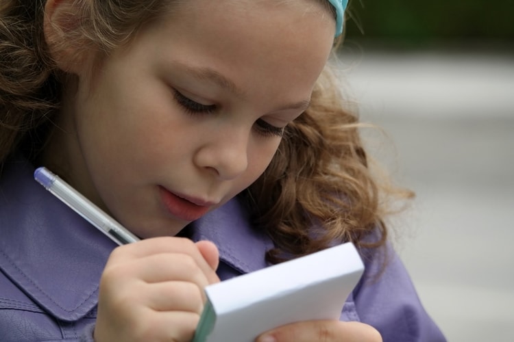 female child writing in a notebook is the best age to learn a language young