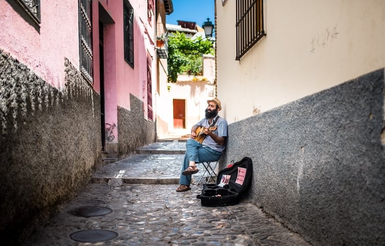 A man in a Spanish alley playing guitar.
