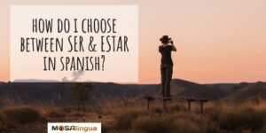 Person wearing cowboy hat, standing back facing camera taking a photo of mountains at sunset. Text reads: How to choose between ser vs. estar in Spanish? MosaLingua