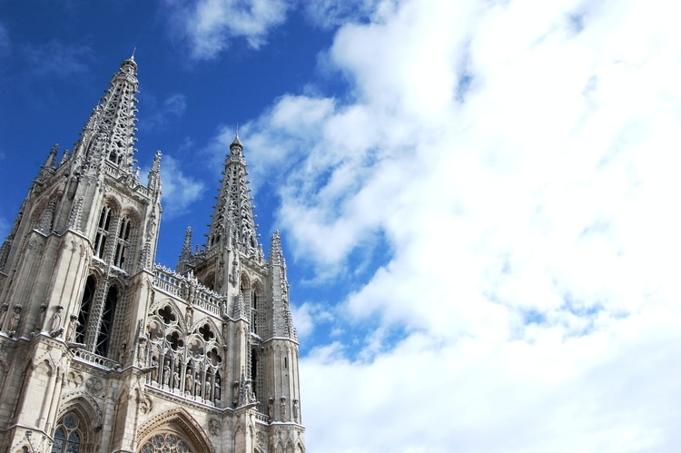The Cathedral of Saint Mary of Burgos in Spain, against a bright blue sky with white clouds.