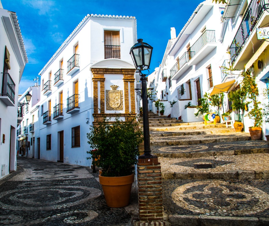 Cobblestone street in Spain, white buildings with balconies. Spanish is one of the easiest languages for English speakers to learn.