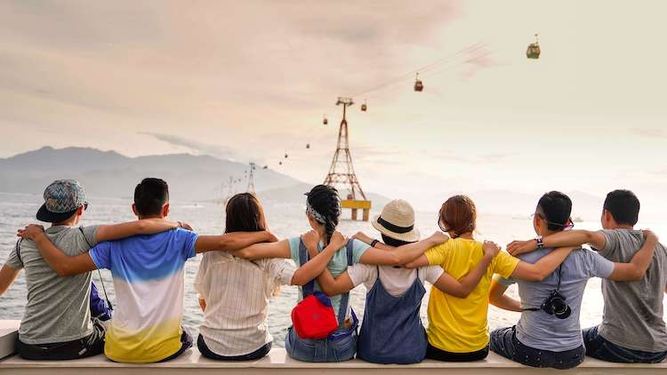 Eight friends sitting with their backs to the camera and their arms around one another, overlooking a body of water. You should never take your friends or family for granted!
