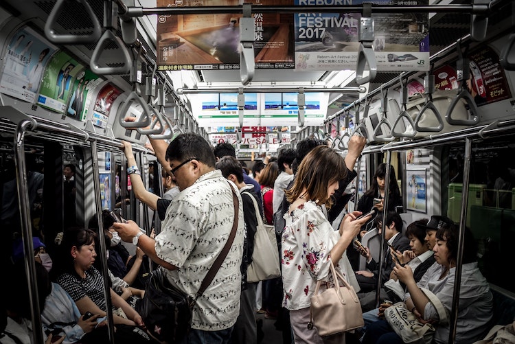 Crowded subway car full of people absorbed by their phones.