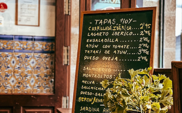 A large chalkboard tapas bar menu in Spanish displaying various Spanish dishes.