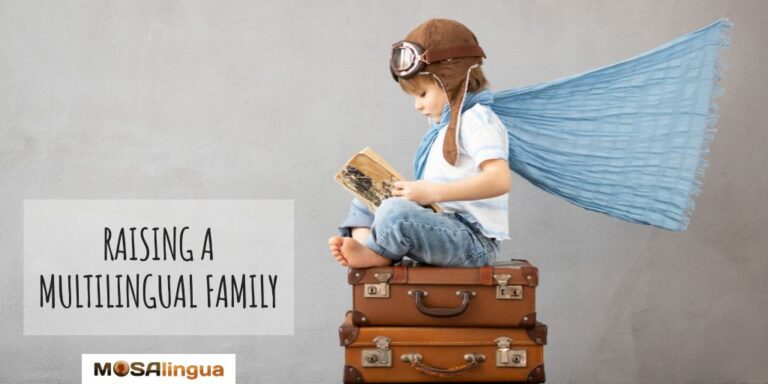 A young child, wearing a vintage pilot helmet and goggles and with a blanket cape wrapped around his shoulders and flowing out behind him, sits crosslegged atop two old leather suitcases, reading a book. Text reads: Raising a multilingual or bilingual family. MosaLingua