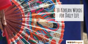 Image of a hand holding a fan painted with Korean spiritual figures. Text reads "10 Korean Words for Daily Life."